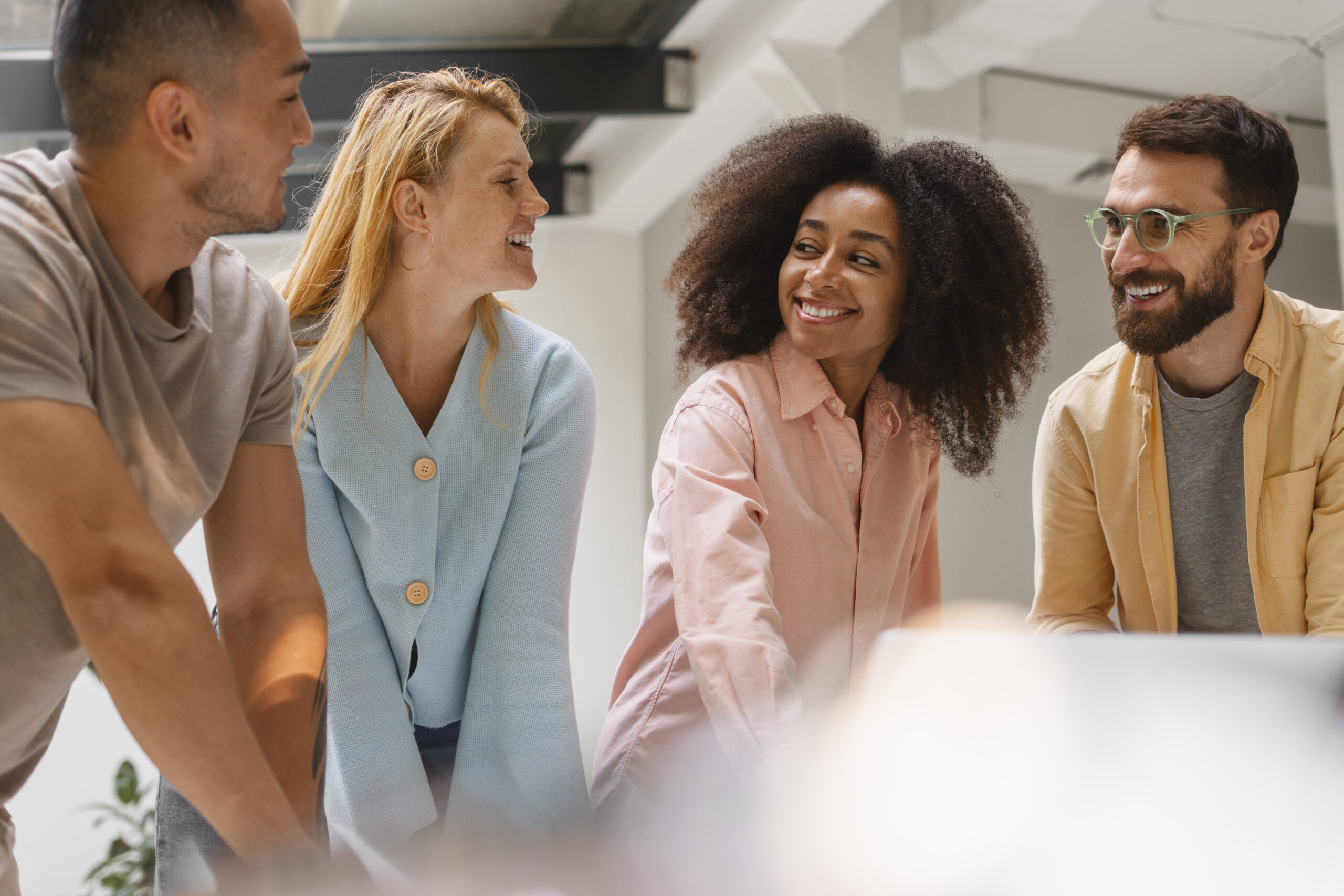 Equipe diversa de profissionais sorrindo em um espaço corporativo, demonstrando um ambiente de trabalho saudável e acolhedor.