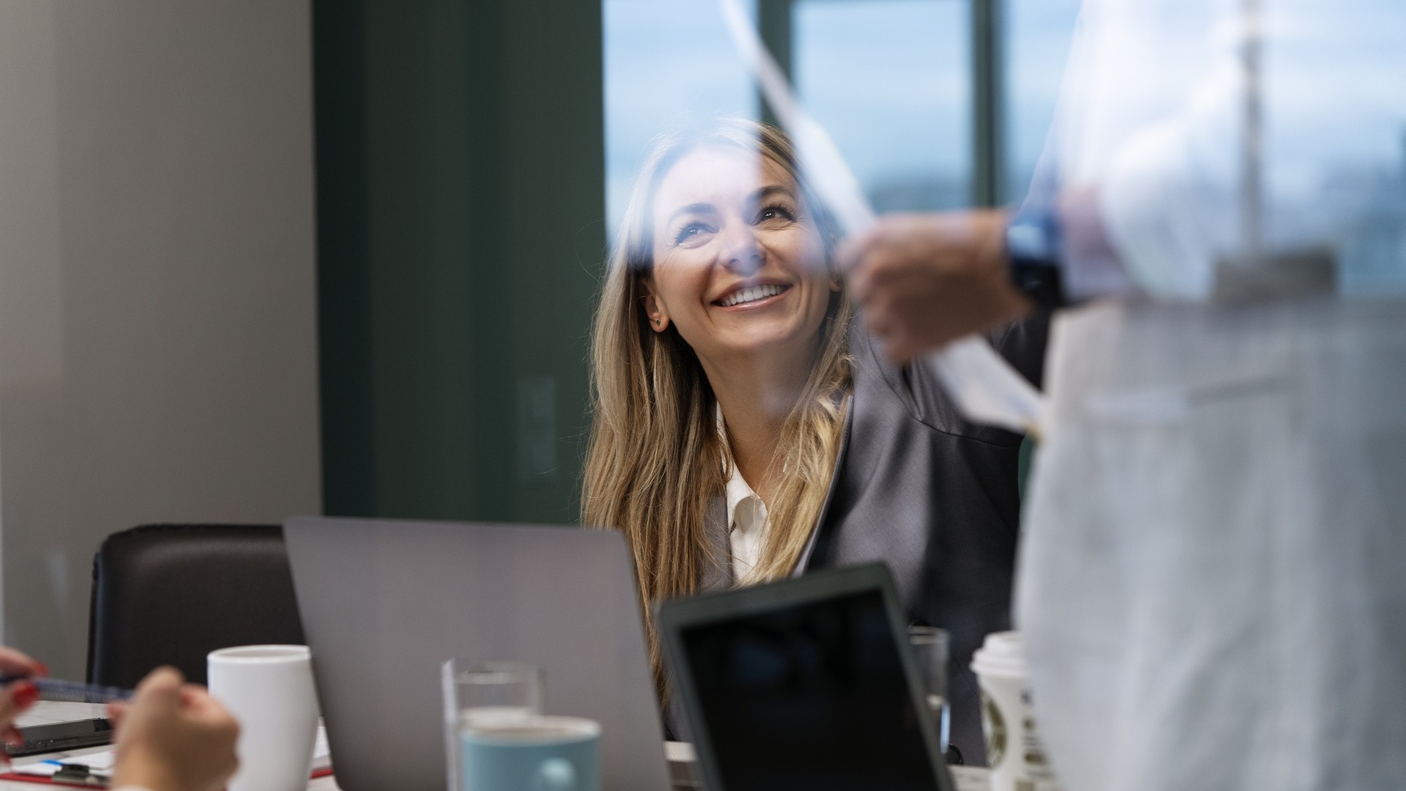 Empresário entregando um cartão de premiação a um colaborador sorridente em um ambiente corporativo.