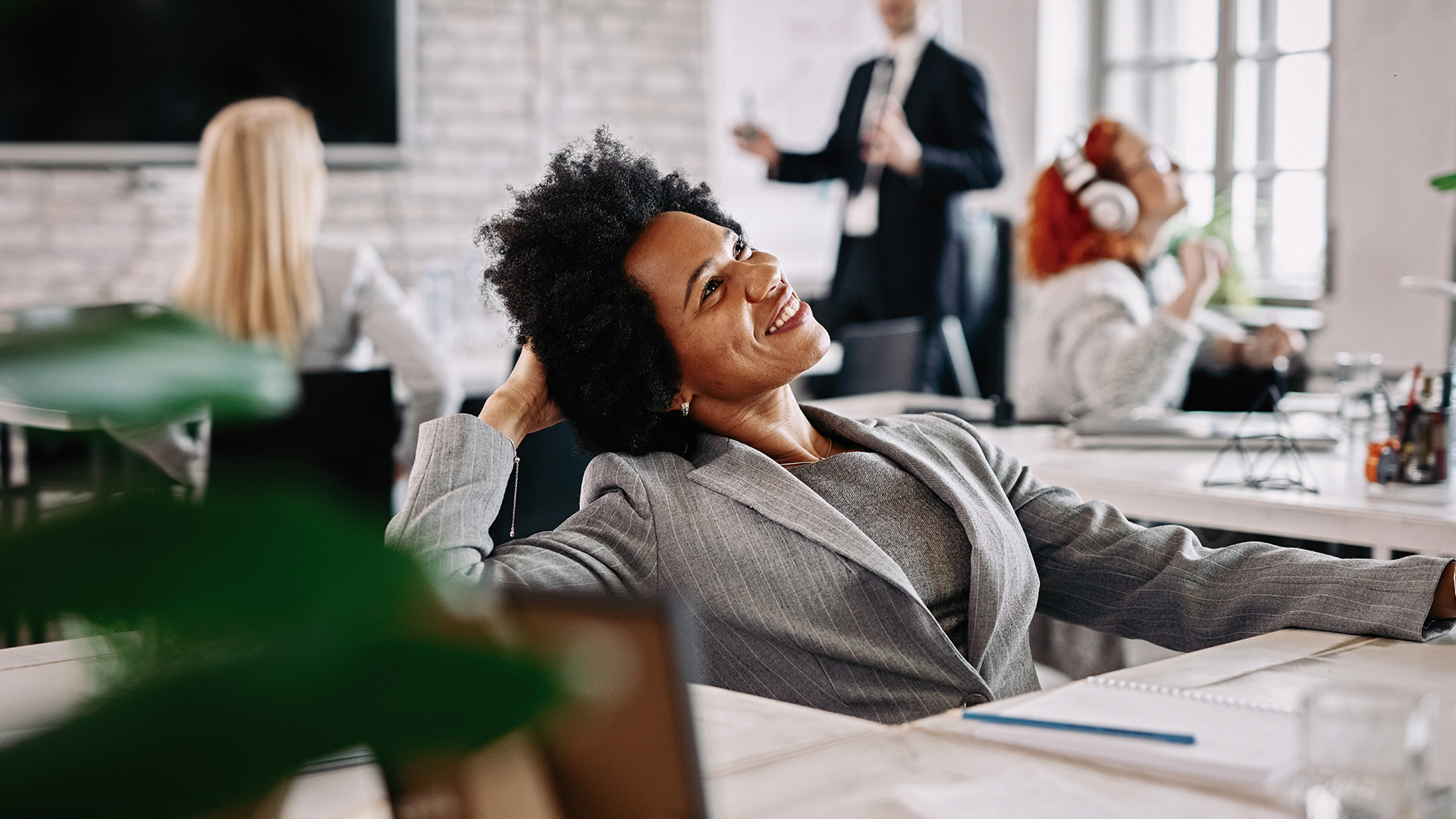 Profissional sorrindo em ambiente corporativo descontraído, representando bem-estar e satisfação no trabalho.