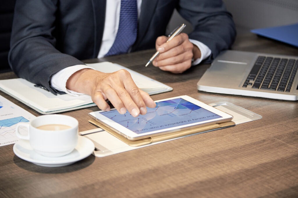 Pessoa segurando cartão corporativo ao lado de planilha digital com gráficos financeiros