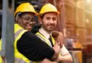 Riscos Psicossociais NR-1: trabalhadores da ind&uacute;stria usando capacete e colete de seguran&ccedil;a em ambiente operacional, representando bem-estar, colabora&ccedil;&atilde;o e cuidado no trabalho.