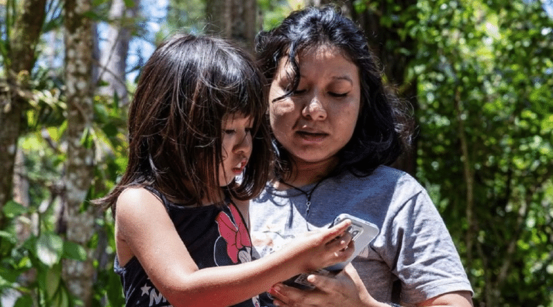 **Alt text:** Mulher e criança observam juntas um celular; imagem ilustrativa de um artigo sobre a Estratégia Nacional de Governo Digital.