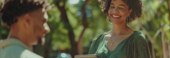 Mulher sorridente segura um tablet durante conversa ao ar livre sobre gest&atilde;o de benef&iacute;cios sociais.