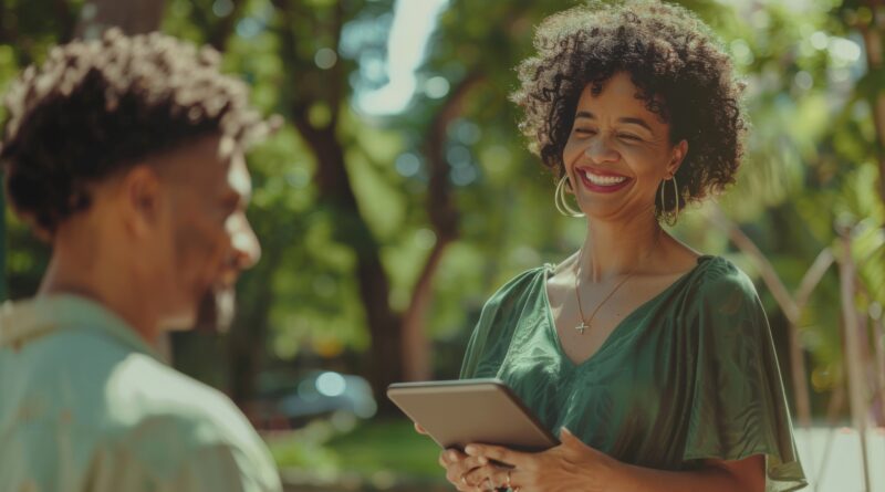 Mulher sorridente segura um tablet durante conversa ao ar livre sobre gest&atilde;o de benef&iacute;cios sociais.